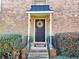 Inviting brick home entrance with a stylish black door, elegant wreath, and well-maintained landscaping at 6980 Roswell Rd # E1, Atlanta, GA 30328