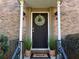 Charming brick home featuring a black front door adorned with a welcoming wreath and potted plants at 6980 Roswell Rd # E1, Atlanta, GA 30328