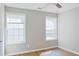 Bedroom with two windows, gray walls, laminate floors, white trim, and light fixtures at 910 Lakeside Ct, Loganville, GA 30052