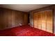 This bedroom features red patterned carpet and light-colored wood walls and trim at 3856 Egypt Rd, Snellville, GA 30039
