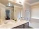 Bright bathroom featuring a double sink vanity with a large mirror and decorative art above the tub at 2620 Sardis Chase Court, Buford, GA 30519