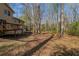 View of the home's backyard featuring mature trees, lush landscaping, and a wooden deck at 3637 Windmill Rd, Ellenwood, GA 30294