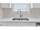 Close-up of a stainless steel kitchen sink with running water and a bright white quartz countertop at 5180 Sterling Trace Nw Ct, Lilburn, GA 30047