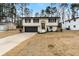 Charming split-level home with a dark garage door, manicured lawn, and neatly trimmed bushes at 6660 Hidden Brook Trl, Atlanta, GA 30349