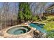 Stone hot tub next to a swimming pool surrounded by trees in a private backyard oasis at 2160 Bradley Trl, Cumming, GA 30041