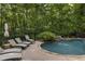 Relaxing backyard features an in-ground pool, stone surround, and comfortable lounge chairs for sunbathing at 2160 Bradley Trl, Cumming, GA 30041