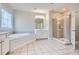 Bright bathroom featuring a soaking tub, glass-enclosed shower, and neutral tile flooring at 489 Carter Se Ave, Atlanta, GA 30317