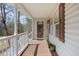 Inviting front porch with a 'Welcome' sign, wood flooring, and a view of the peaceful surroundings at 76 Riverbend Trl, Douglasville, GA 30134