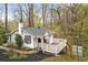 Charming cottage-style home with white exterior, a deck, and mature trees in a wooded setting at 106 Maple St, Roswell, GA 30075