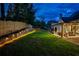 Backyard patio with ambient lighting, a spacious lawn, and illuminated retaining wall in the evening at 237 Webney Se Dr, Marietta, GA 30068