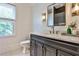 Modern bathroom featuring dark vanity, marble countertop, decorative lighting, and large window at 237 Webney Se Dr, Marietta, GA 30068