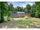 A backyard view of the house that includes a small deck, gray vinyl siding, green grass, and beautiful green trees at 4720 Timberland Sw Dr, Mableton, GA 30126