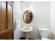 Powder room featuring a pedestal sink, oval mirror, and a classic wooden door at 4720 Timberland Sw Dr, Mableton, GA 30126