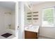 Bright bathroom featuring a shower-tub combo, vanity with sink, floating shelves, and natural light from the window at 4720 Timberland Sw Dr, Mableton, GA 30126