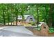 Charming home exterior with a brick foundation, manicured lawn, tall trees, and a curved driveway at 4720 Timberland Sw Dr, Mableton, GA 30126