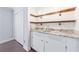 Convenient wet bar featuring open shelving, granite countertops, and white cabinetry at 13 Ivy Ne Sq, Atlanta, GA 30342