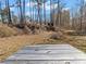 A wooden deck overlooks a spacious lot with towering trees offering endless possibilities for outdoor enjoyment at 8470 Wallace Tatum Rd, Cumming, GA 30028