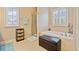 Bathroom with tiled shower, soaking tub under window, and dark-wood accent basket storage at 300 South Village Sq, Canton, GA 30115