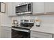 Close up of modern stainless steel range and microwave against a white subway tile backsplash and gray cabinetry at 312 Navigator Ln, Mcdonough, GA 30253