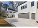 Exterior view of a modern home with a large driveway and two-car garage, enhanced by a lush tree line at 1800 Charles Nw Pl, Atlanta, GA 30318