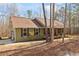 Inviting single-story home featuring a cozy front porch, brown roof, and green siding nestled amongst mature trees at 138 Rutledge Rd, Temple, GA 30179