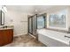 A well-lit bathroom boasts a soaking tub, glass shower and vanity with granite countertop at 2145 Red Barn Ct, Cumming, GA 30040