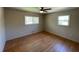 This bedroom has hardwood floors, fresh paint, a ceiling fan, and two windows at 445 Royal Oaks Ter, Stone Mountain, GA 30087