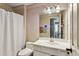 Bathroom with white sink, toilet, vanity, and shower with patterned wallpaper at 5163 Holly Springs Dr, Douglasville, GA 30135