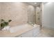 Bright bathroom featuring tub with shower, neutral tile, and modern fixtures at 5805 Clarion St., Cumming, GA 30040