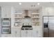 Modern kitchen with stainless steel appliances, white cabinets, and open shelving against a brick wall at 5805 Clarion St., Cumming, GA 30040