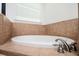 Close up of relaxing soaking tub with tiled surround and brushed nickel fixtures near window with blinds at 1112 Park S Row, Atlanta, GA 30312