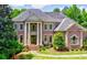 Grand brick home featuring stately columns, arched windows, mature trees, and lush landscaping at 2698 Bonar Hall Path, Duluth, GA 30097