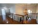 Upstairs hallway with gleaming hardwood floors, chandelier, and decorative wrought iron railing at 2698 Bonar Hall Path, Duluth, GA 30097