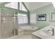 Bright bathroom featuring a walk-in shower, tub, vanity, and a large window for natural light at 1673 Chadwick Ridge Dr, Lawrenceville, GA 30043