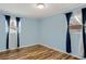Light blue bedroom features wood-look floors, curtains, and natural light at 6370 Boca Grande Blvd, Forest Park, GA 30297