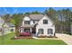 Beautiful white brick home with a well-manicured lawn and professional landscaping and dark shuttered windows at 6825 Concord Brook Ln, Cumming, GA 30028