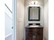 Bathroom with wood vanity, black countertop, rectangular mirror, and access to the staircase at 1561 Cooks Pond Dr, Powder Springs, GA 30127