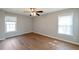Spacious bedroom with hardwood floors, ceiling fan, and two large windows offering ample natural light at 1561 Cooks Pond Dr, Powder Springs, GA 30127