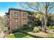 A multi-Gathering, brick building with multiple balconies, shrubbery, and mature trees at 5910 Bond St # 401, Cumming, GA 30040