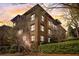 Multi-story brick building with mature trees and lush landscaping at sunset at 5910 Bond St # 401, Cumming, GA 30040