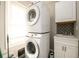 Well-lit laundry room features stacked washer and dryer and a sink with updated backsplash at 2107 Penrose Dr, Atlanta, GA 30344