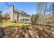 Elegant brick home featuring covered porches and a lush lawn, bordered by a wooded area at 305 Inman Pl, Roswell, GA 30075