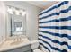 Bathroom showcasing a vanity with a gray cabinet and a shower-tub with a blue and white striped curtain at 305 Inman Pl, Roswell, GA 30075