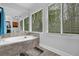 Bright bathroom with a soaking tub surrounded by tiled walls, and a large window overlooking the yard at 4495 Sagebrush Nw Dr, Kennesaw, GA 30152