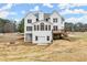 White, two-story home has a backyard with a deck, patio, fire pit, and tiered retaining walls at 636 Ginger Cake Rd, Fayetteville, GA 30214