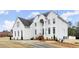 Elegant, multi-story, white home with black roof, well-manicured landscaping and a long driveway at 636 Ginger Cake Rd, Fayetteville, GA 30214