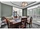 Dining room has a dark color scheme with a wooden table and chairs, a light fixture, and bright natural light at 269 Hidden Wood Ct, Lawrenceville, GA 30043