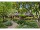 Serene home exterior surrounded by vibrant landscaping, mature trees, and a stone pathway at 1050 E Club Ne Ln, Atlanta, GA 30319