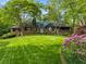 Charming stone cottage-style home with a lush green lawn, mature trees, and blooming flowers at 1050 E Club Ne Ln, Atlanta, GA 30319