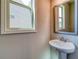 Bright bathroom featuring a pedestal sink with a framed mirror and a window providing natural light at 293 Depot Landing Rd, Auburn, GA 30011